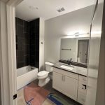 Modern bathroom featuring a black-tiled shower, white vanity with a black countertop, and sleek black fixtures. Painted in PPG Fog (1010-2) Eggshell for a contemporary finish.