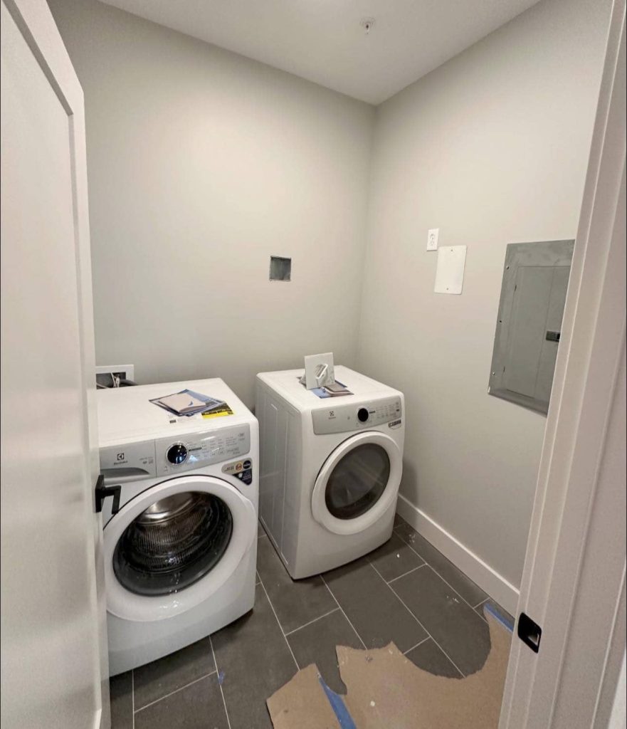 Compact laundry room featuring a white washer and dryer, painted in PPG Fog (1010-2) Eggshell.