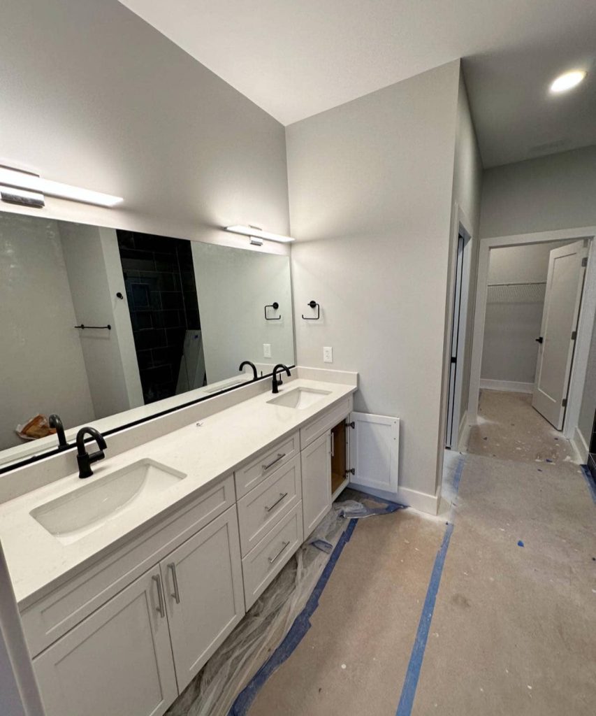 Modern master bathroom featuring a double-sink white vanity, black fixtures, and a large mirror, painted in PPG Fog (1010-2) Eggshell.