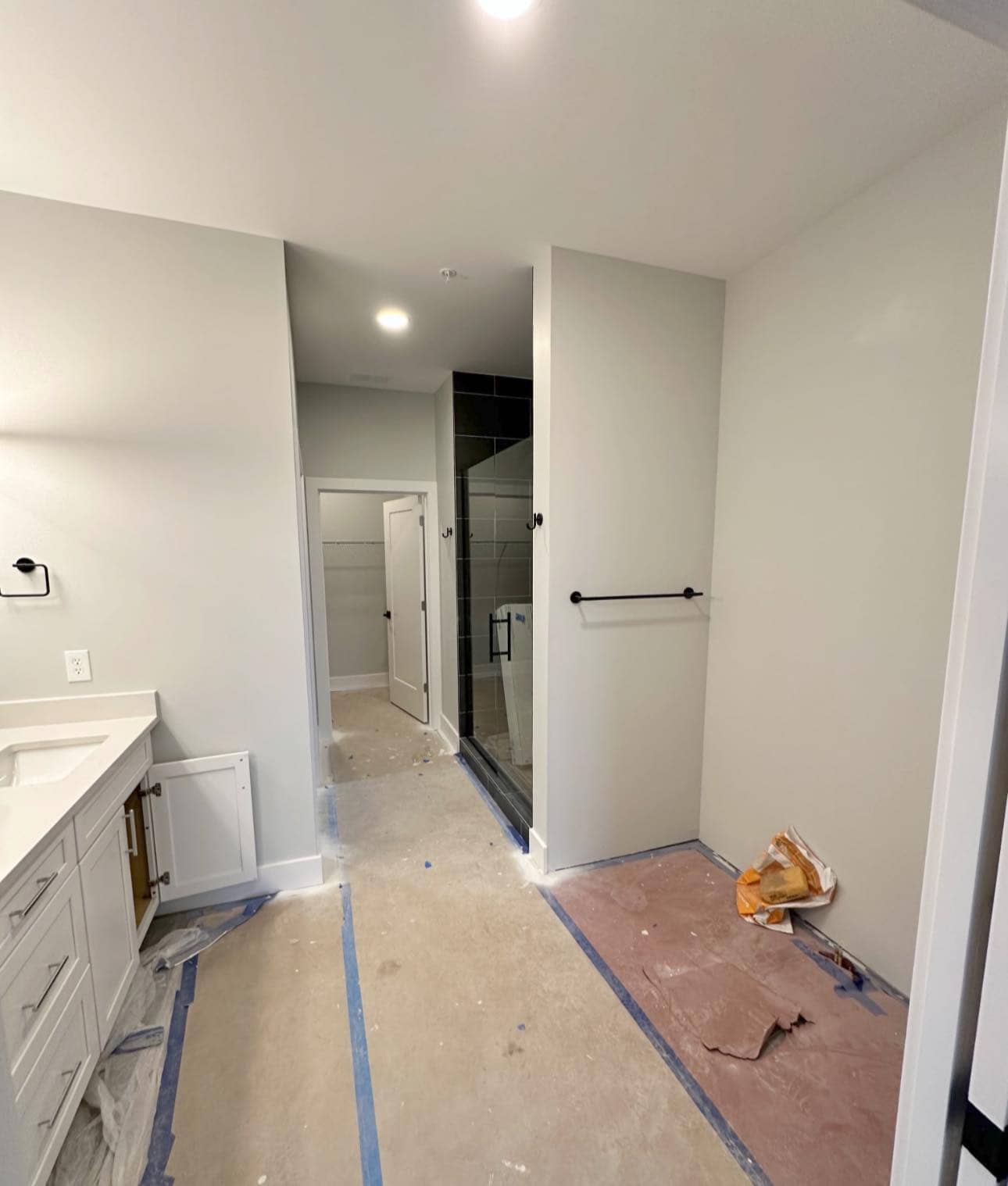 Master bathroom featuring a walk-in shower with black tiles, black fixtures, and a spacious vanity area.