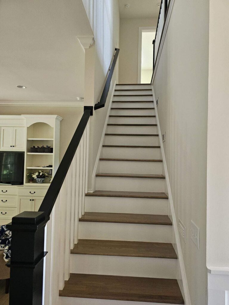 Brightly painted staircase with wooden steps and black handrail in Feather Dawn OC-06 by Benjamin Moore